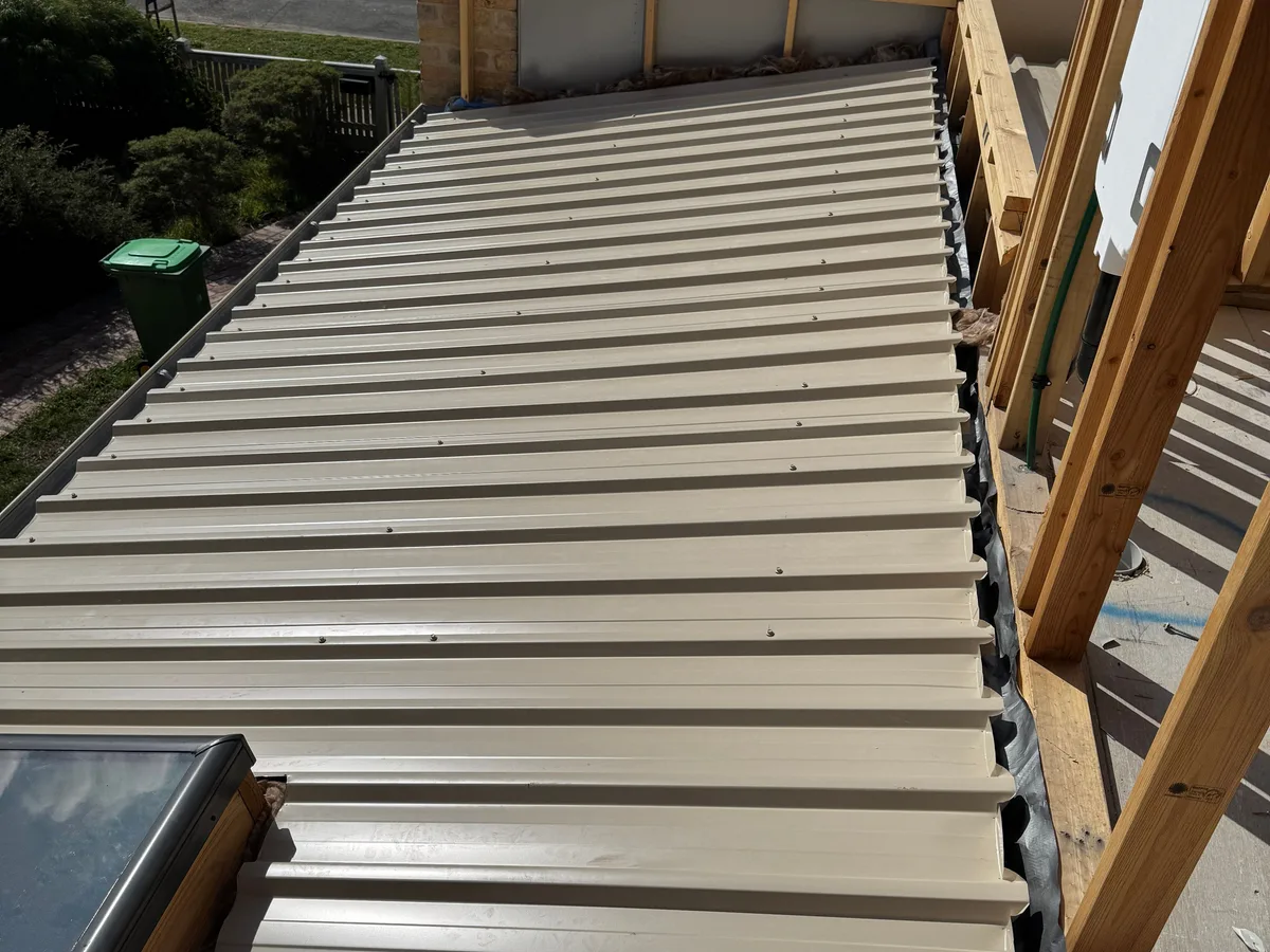 The same extension roofed in beige metal sheets, photographed from the opposite end