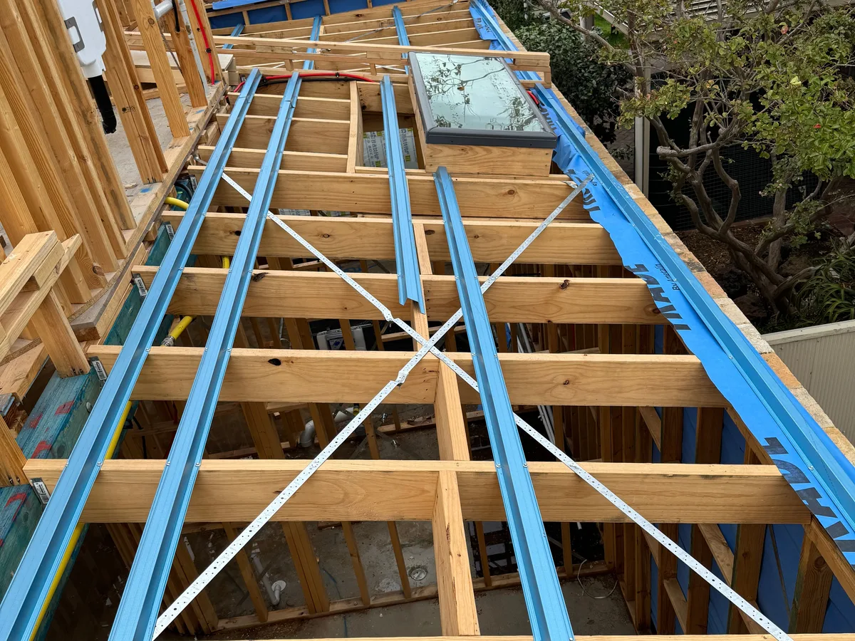 Timber and steel roof framing for an extension, with a roof window frame in place
