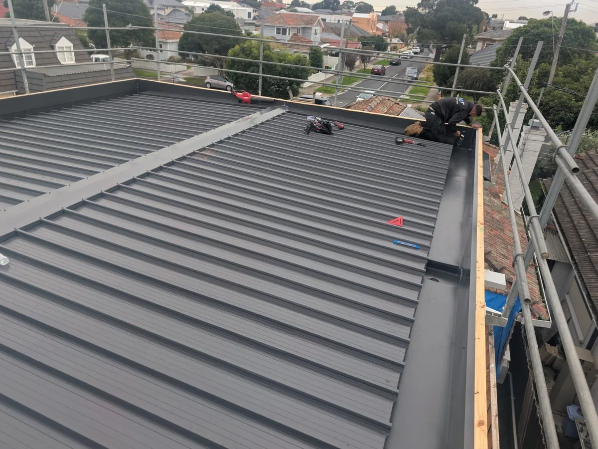 The same roof with dark metal roofing installed with a box gutter along the edge