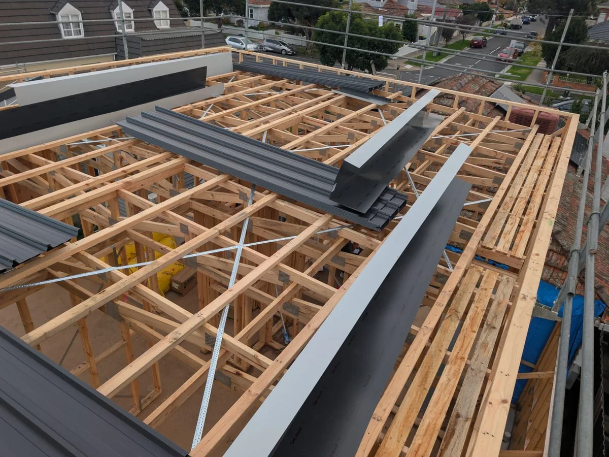 Timber roof frame with new metal sheets stacked ready to install