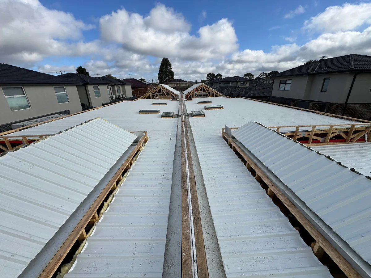 The same townhouse roofs sheeted in light metal roofing with a central gutter