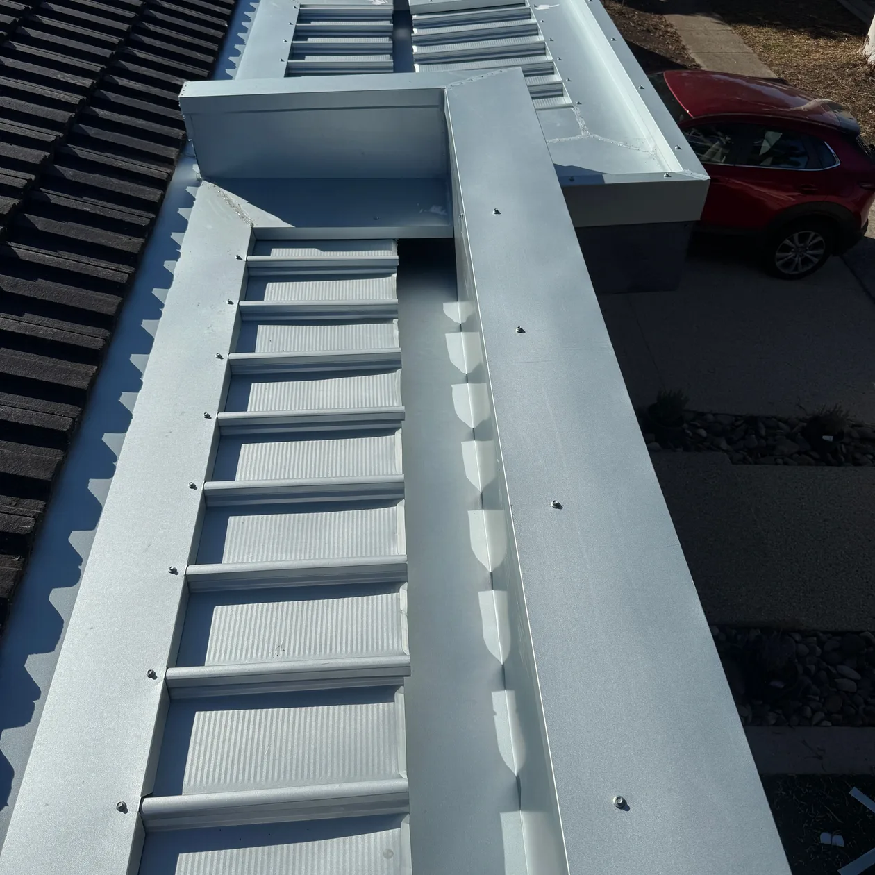Metal box gutter and flashings running beside a tiled roof