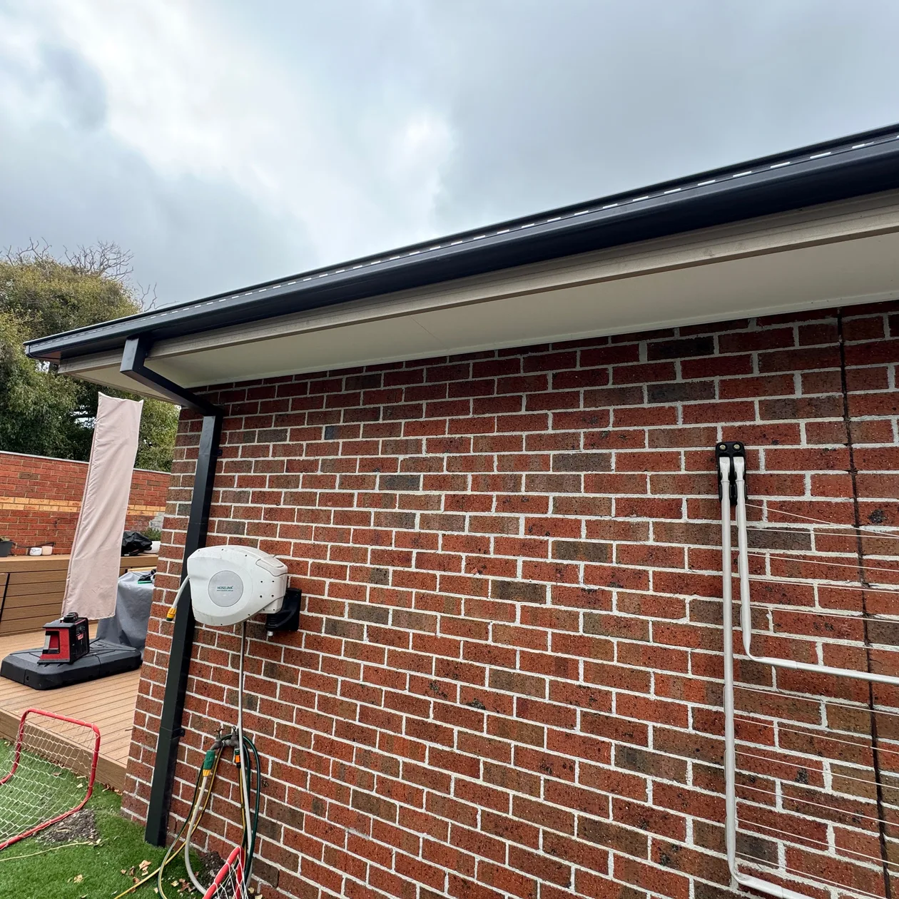 Dark gutter and downpipe on the side of a red brick home