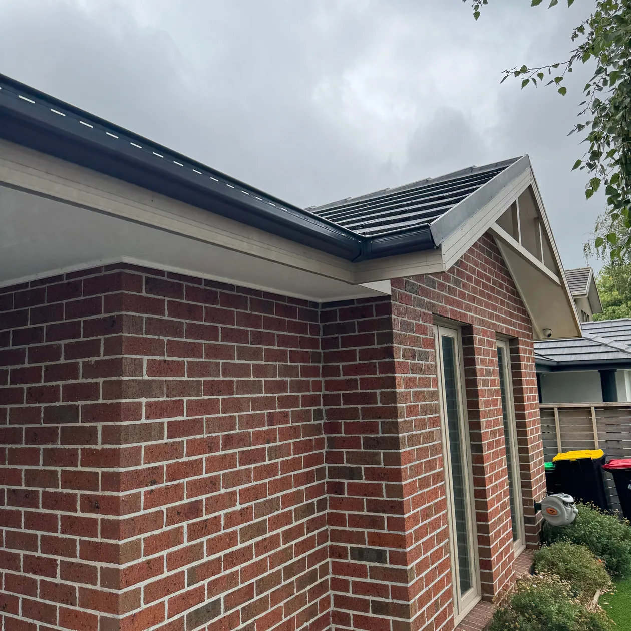Red brick home with dark fascia and gutter
