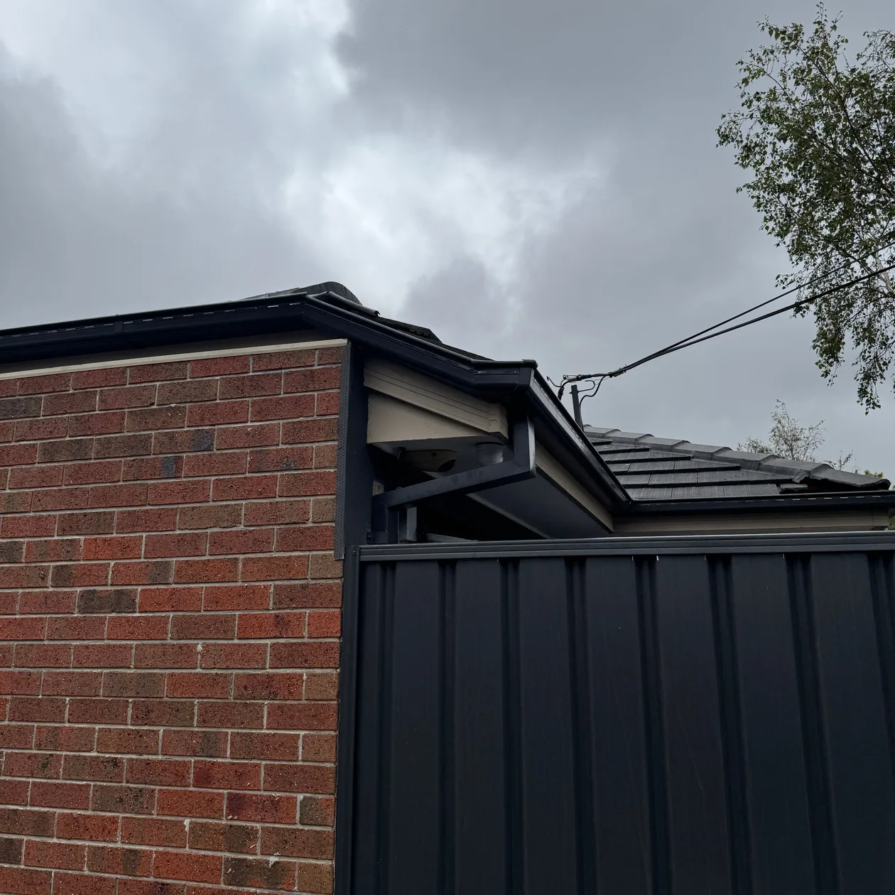 Dark metal gutter running along the eaves of a brick home