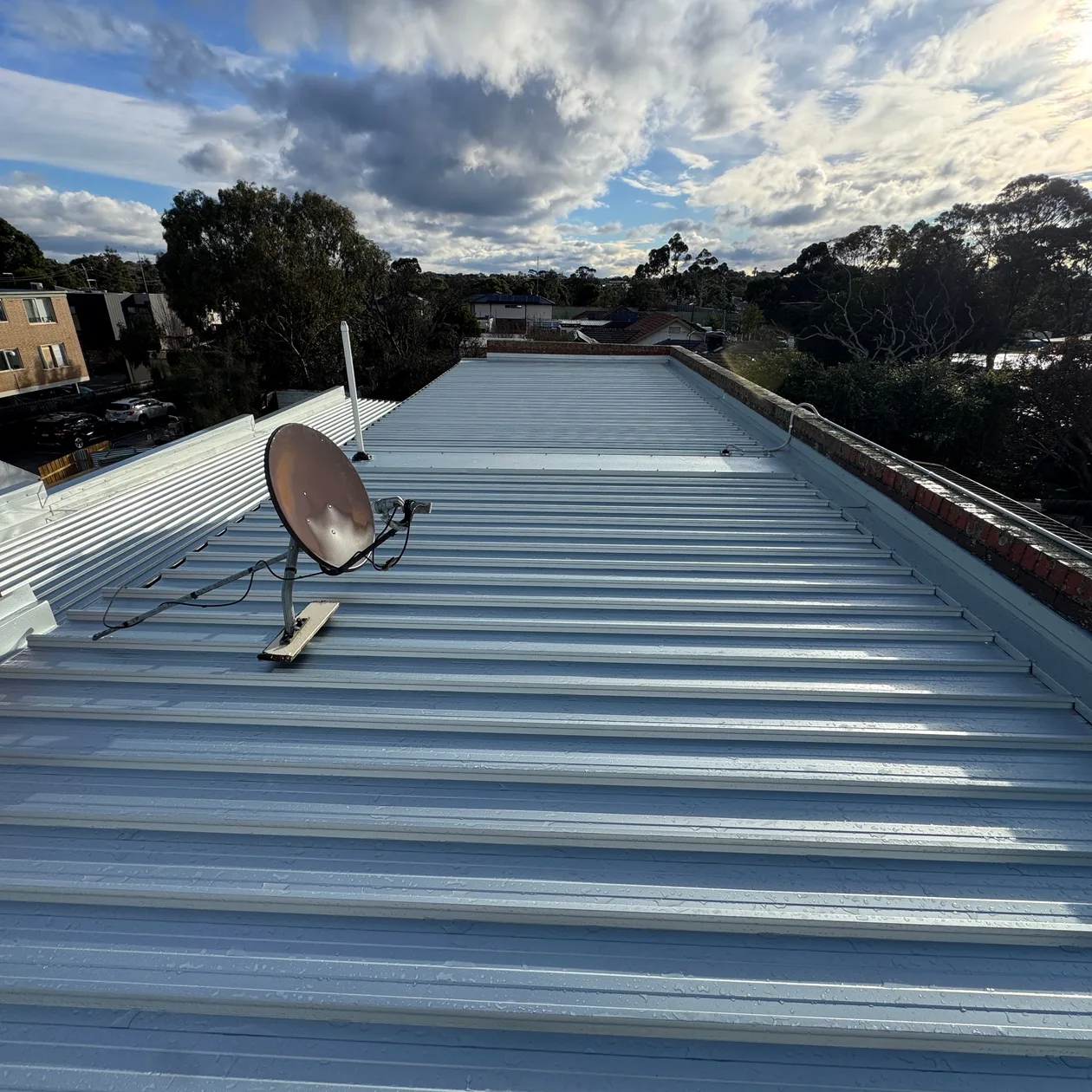 Long low-pitch metal roof run beside a brick parapet wall