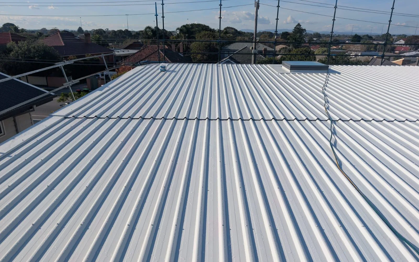 Corrugated metal roof looking out over surrounding suburban rooftops