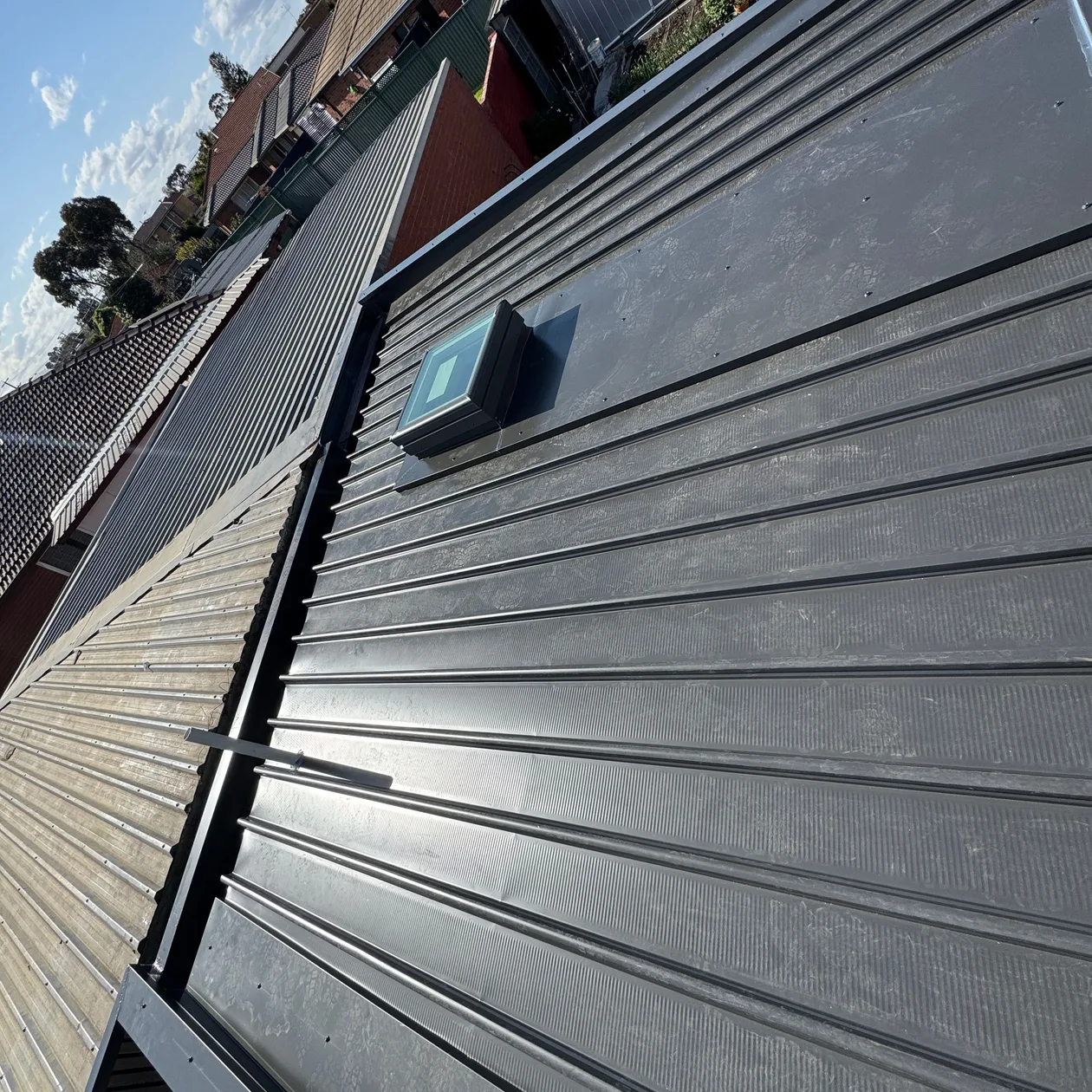 Dark metal roof with a flashed roof window and a box gutter along the edge