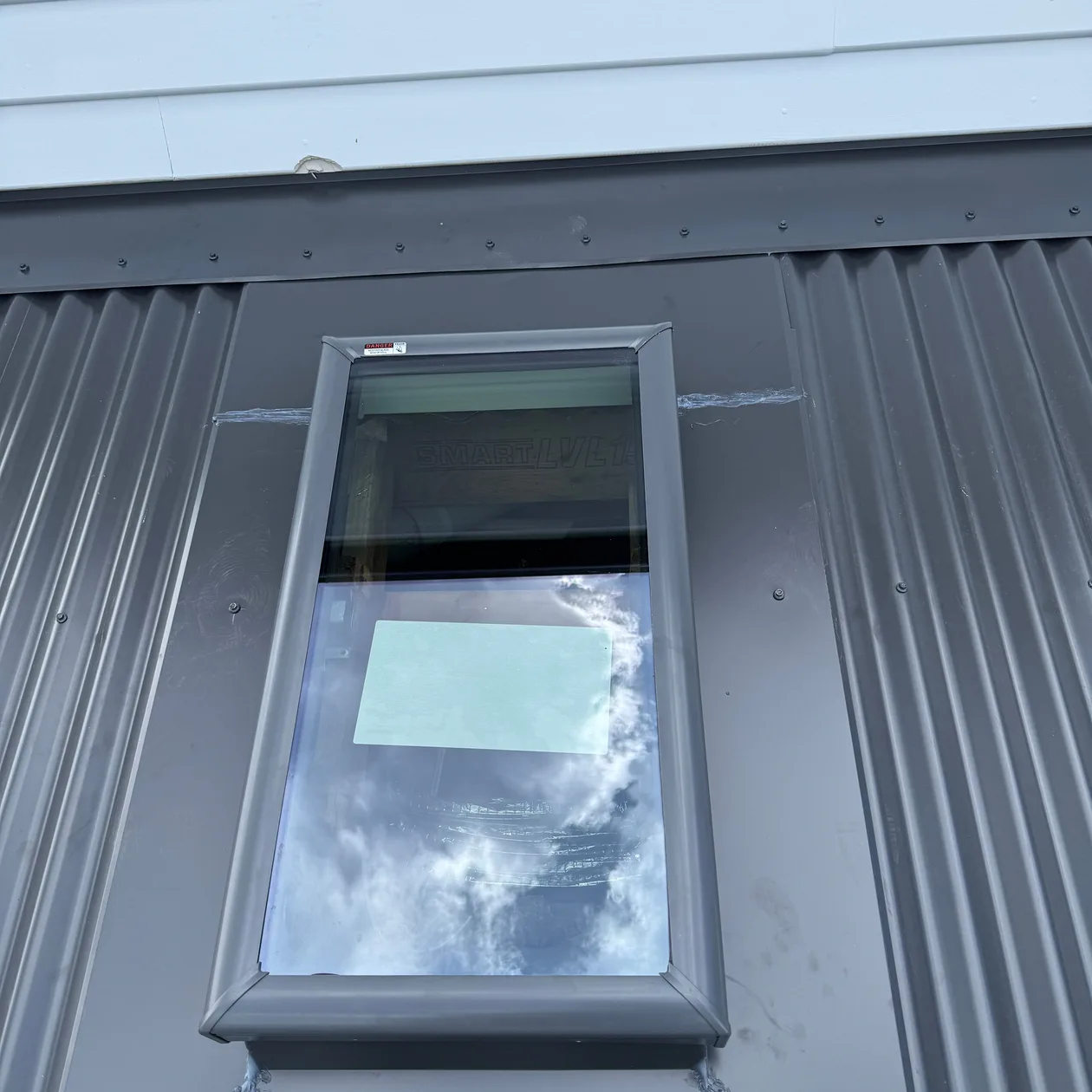 Metal flashing around a roof window on a dark metal roof