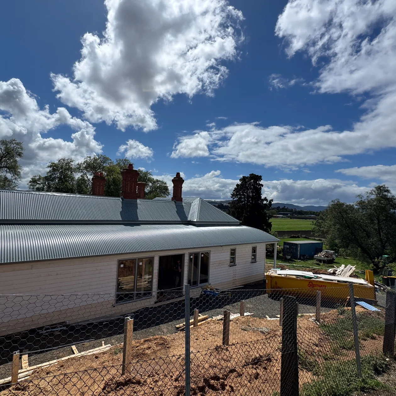 Corrugated metal roof on a single-storey weatherboard home with brick chimneys