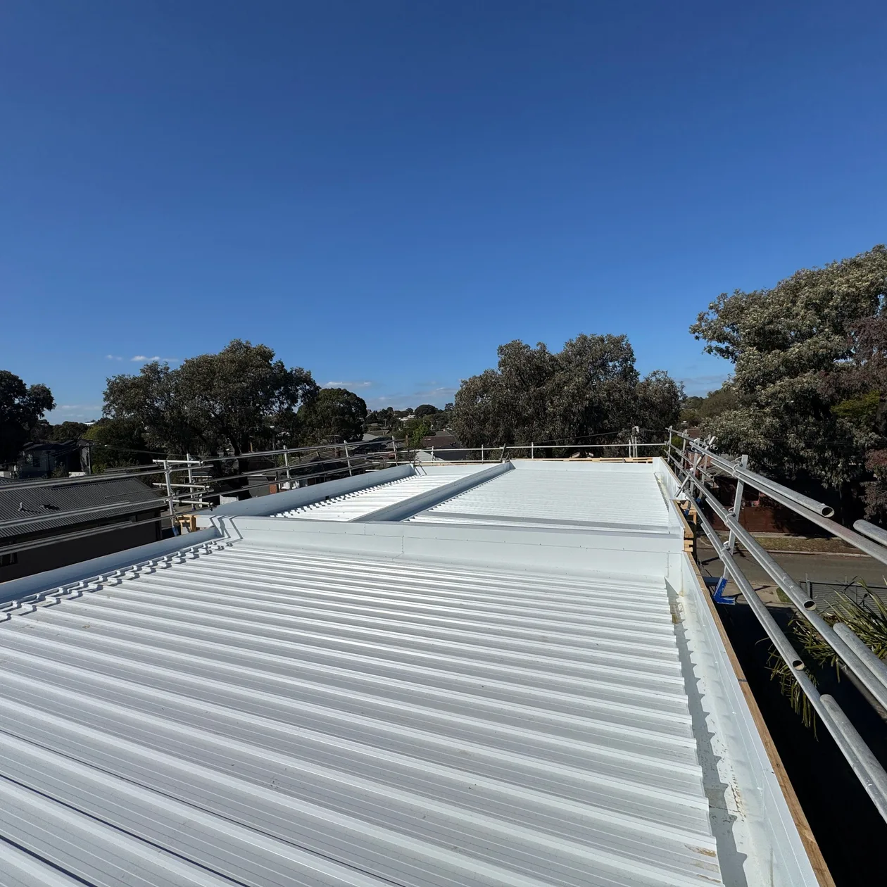 Long pale low-pitch metal roof with an edge rail