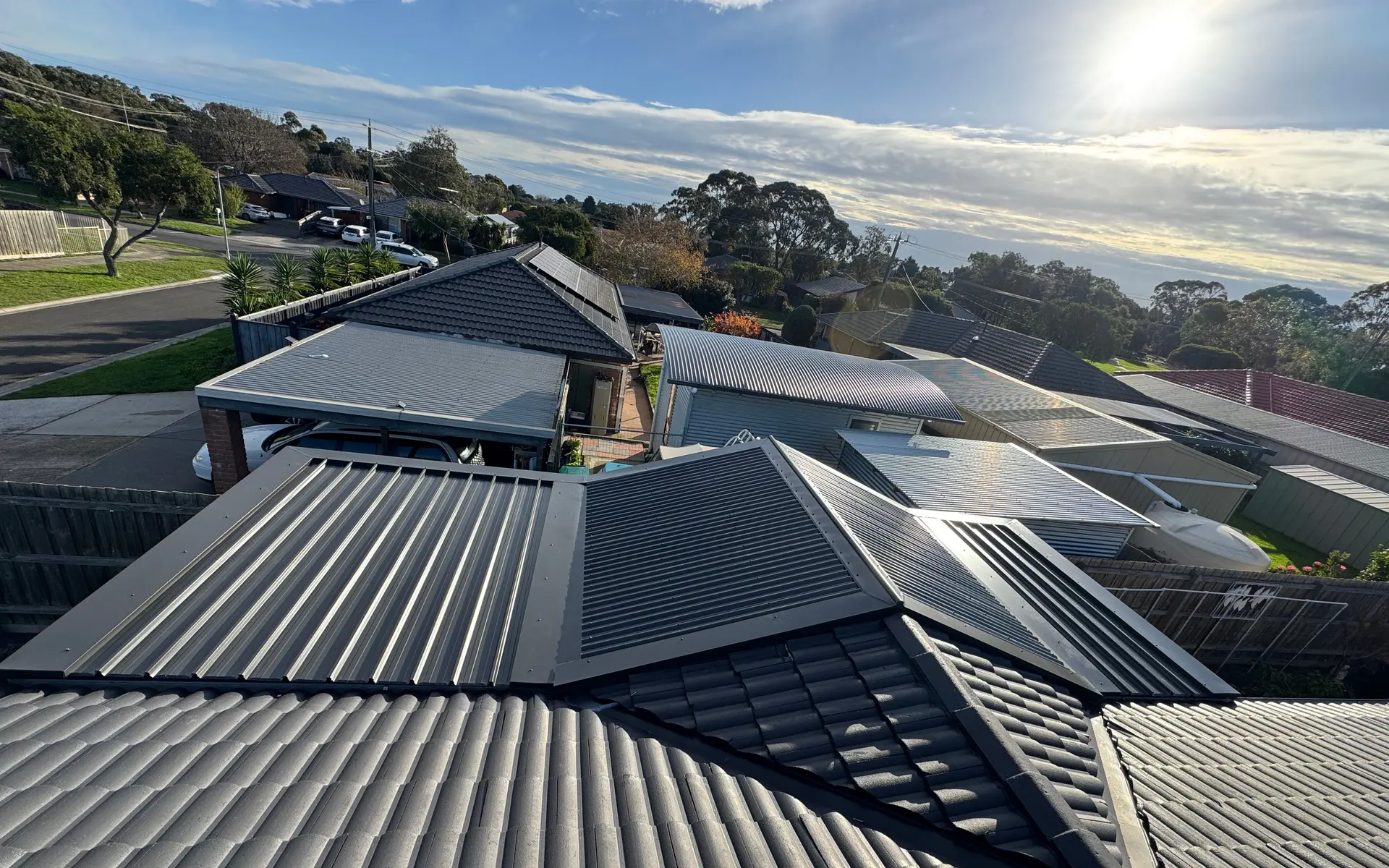 New dark metal roof section on a tiled suburban home with neighbouring rooftops behind