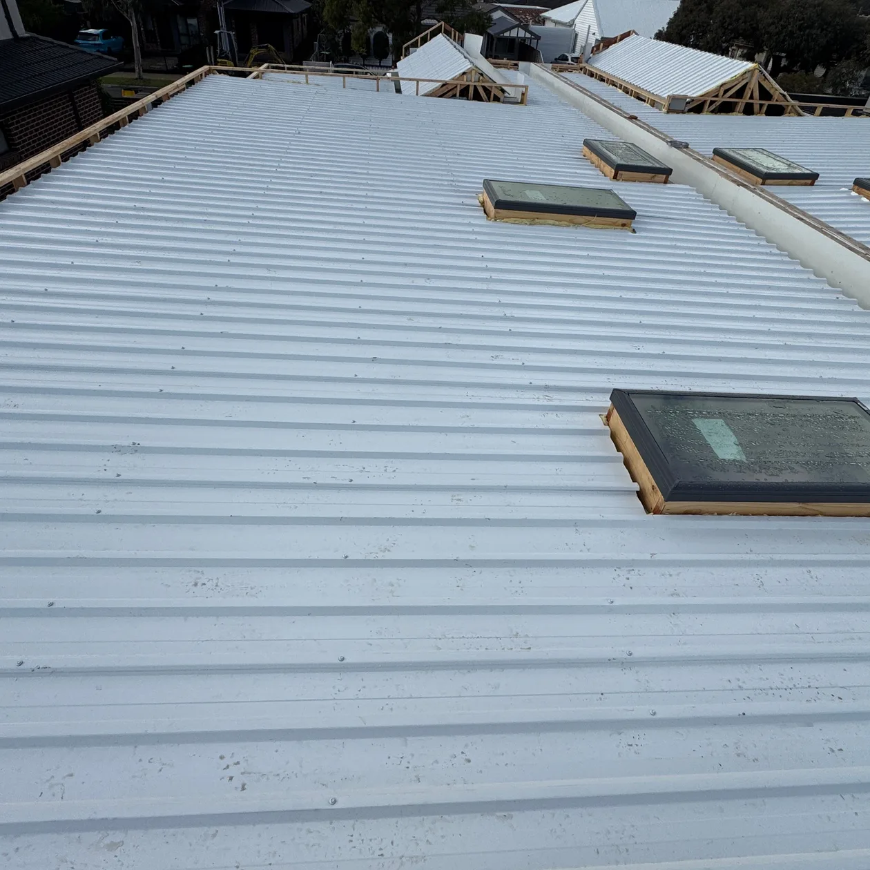 Pale metal roofs across a new townhouse development with roof windows
