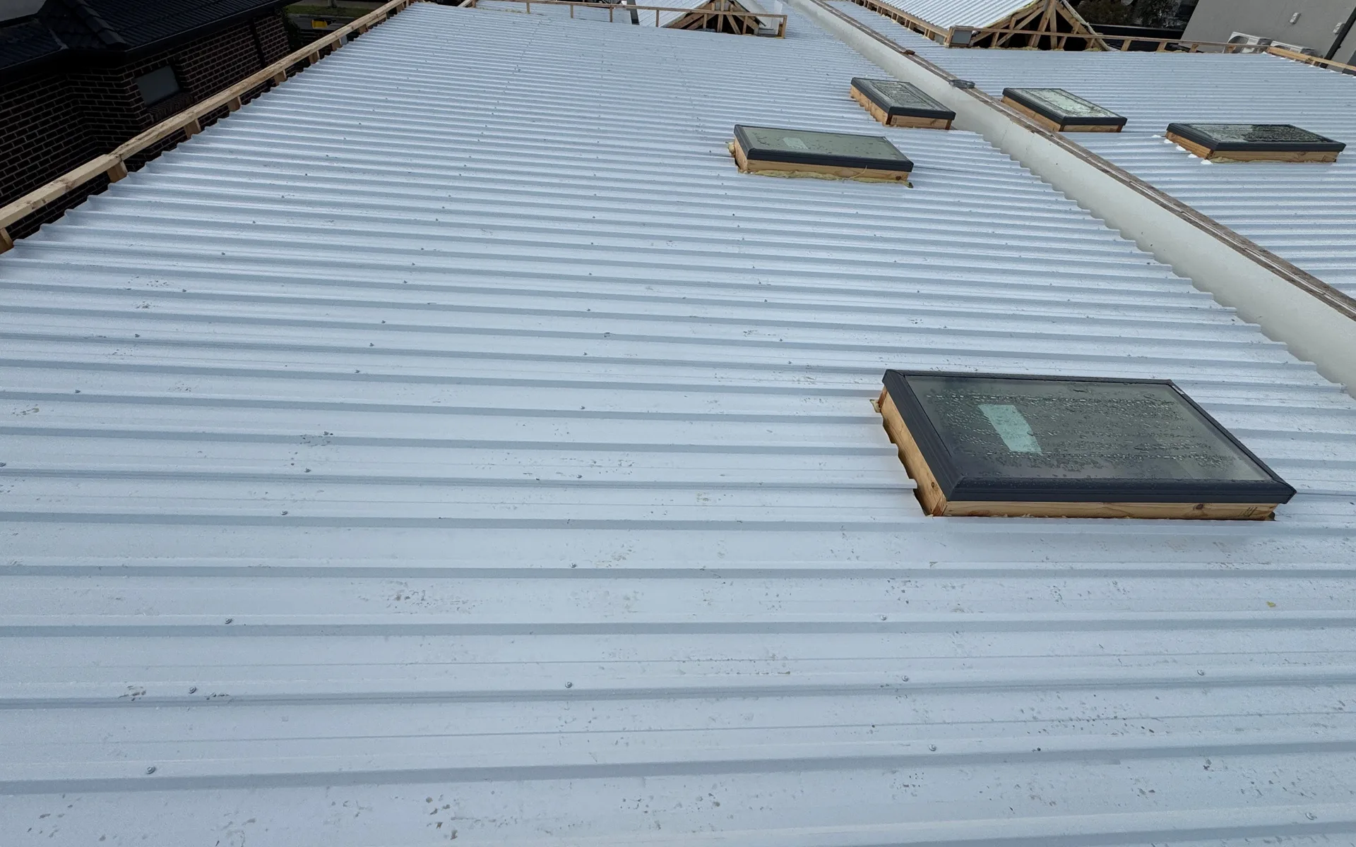 Pale metal roofs with roof windows across a townhouse development