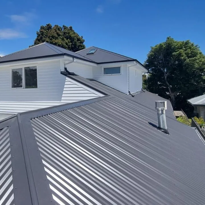 Two-storey white home above a grey corrugated metal roof