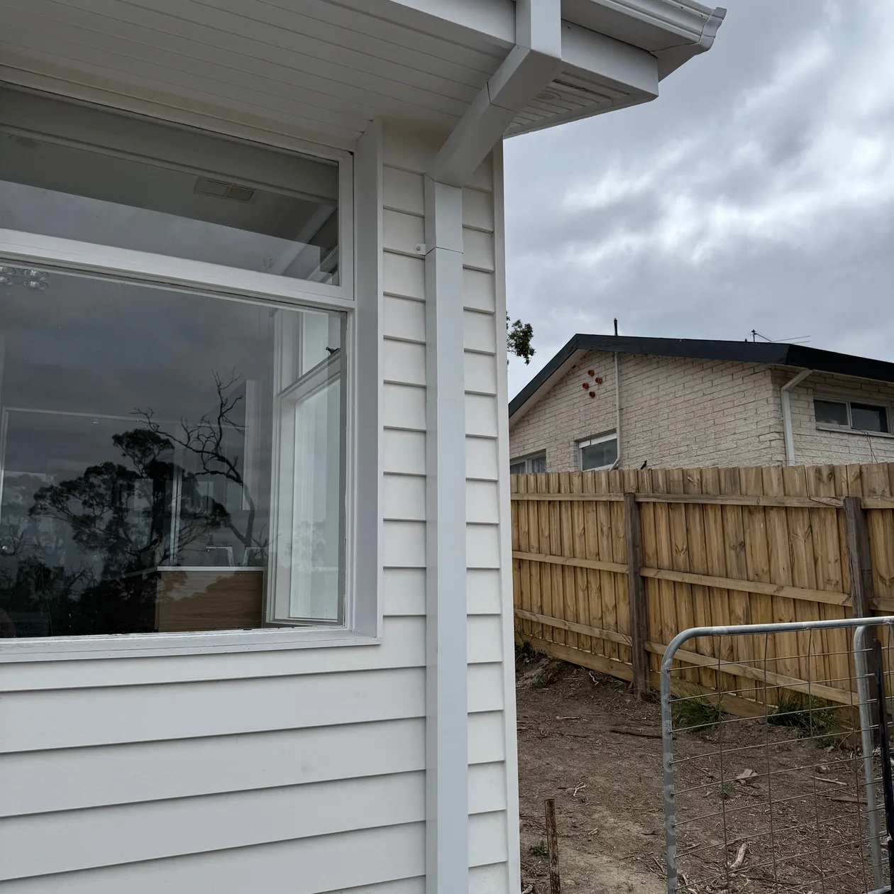 White weatherboard home with a gutter and downpipe at the corner