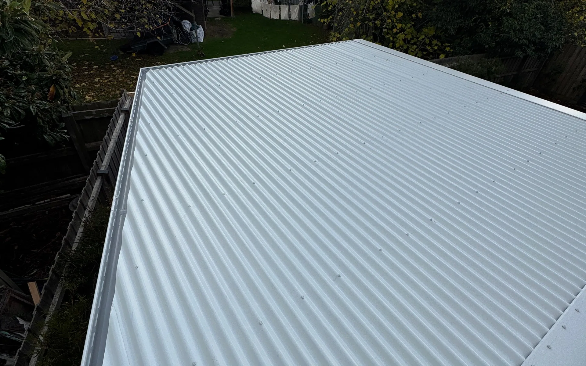Pale corrugated metal roof surrounded by garden trees